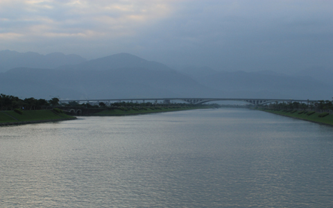 傍晚日落，從冬山河親水公園的利澤簡橋往北宜高速通路望去，河道與橋與山
